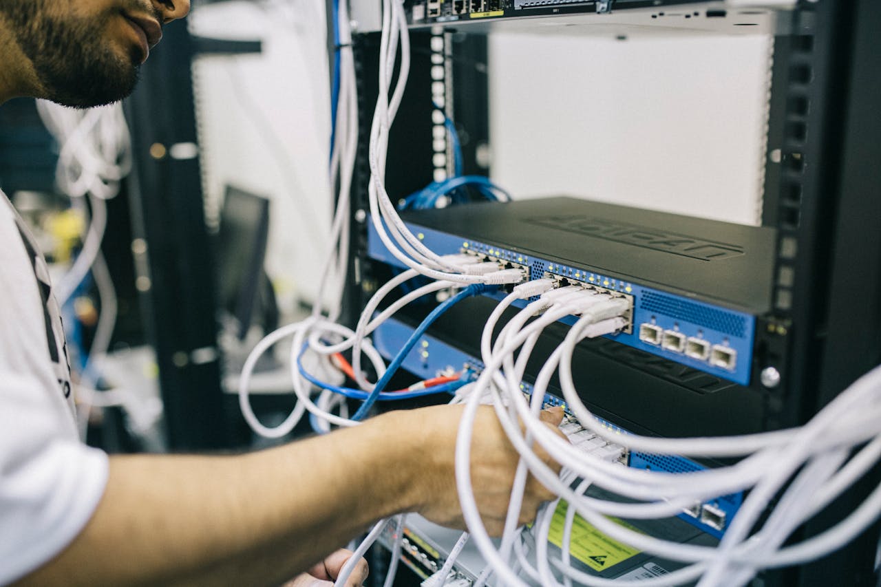 gallery-02 An IT professional configuring network cables in a server rack, focusing on Ethernet connections.