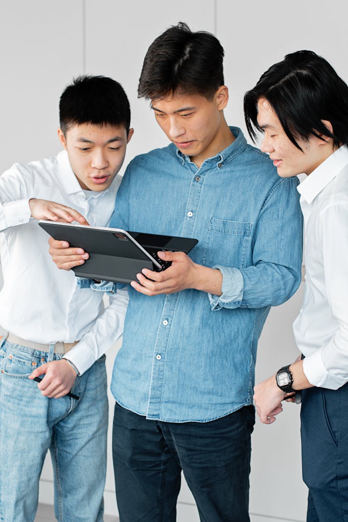 our-story Three young men discussing work on a tablet in a modern office setting.